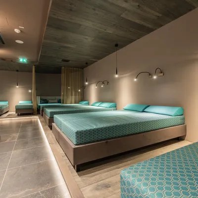 Modern spa relaxation room with multiple teal lounge beds and ambient lighting